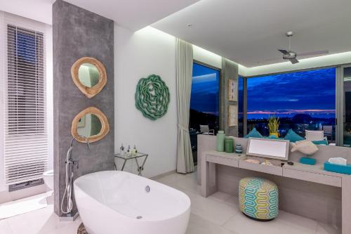 a bathroom with a white tub and a large window at Villa Omari 5Bedroom with pool in Kata Beach