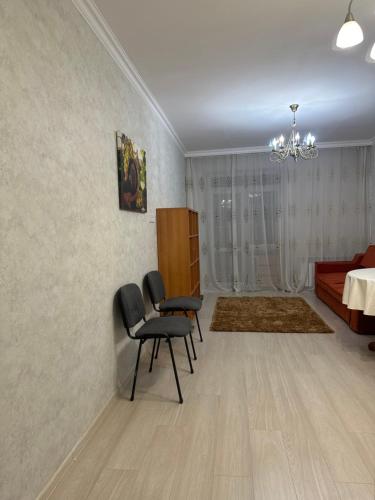 uma sala de estar com duas cadeiras e uma cama em однокомнатная квартира em Prigorodnyy