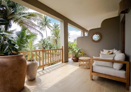 a living room with a chair and a balcony with palm trees at The Jam House in Ahangama