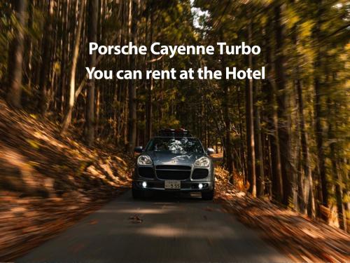 a car parked on a road in a forest at Hotel Montblanc Hakuba in Hakuba