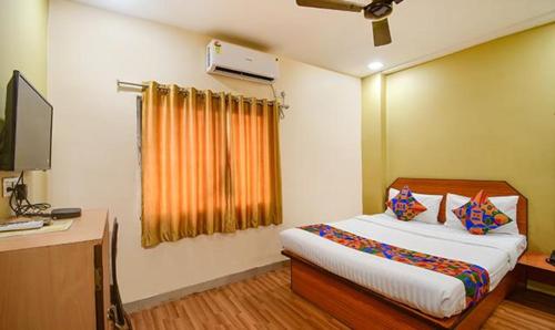 Dormitorio con cama, escritorio y TV en FabHotel Kamala Inn en Kotrung