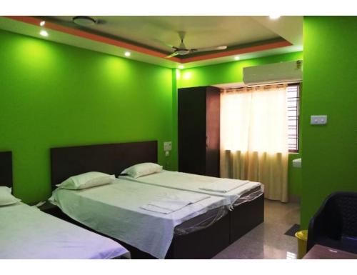 Habitación verde con 2 camas y ventana en Hotel Invite, Agartala en Agartala
