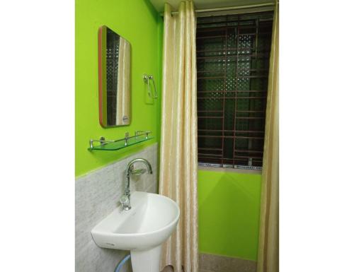 a green bathroom with a sink and a mirror at Hotel Invite, Agartala in Agartala