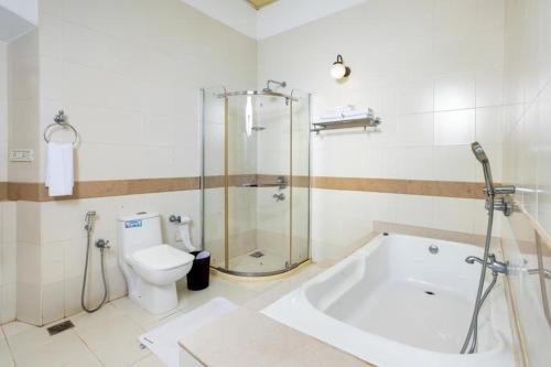 a bathroom with a shower and a tub and a toilet at Koder House in Cochin