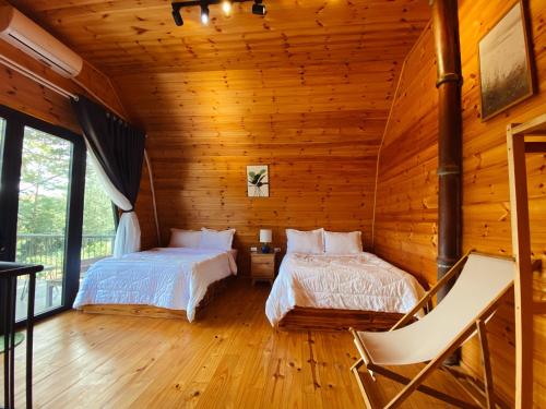 a bedroom with two beds in a log cabin at T'MĂNG ĐEENG HOMESTAY in Kon Von Kla