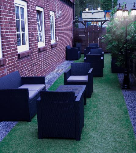 a row of chairs sitting on the grass next to a brick building at Hotel Ammerland garni in Wilhelmshaven
