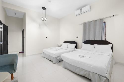 ein Schlafzimmer mit 2 Betten und einem Stuhl darin in der Unterkunft Terminal Majesty Villa Haven 3bedroom near DXB T3 in Dubai
