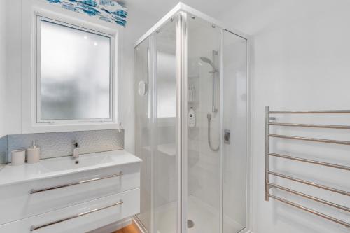 bagno bianco con doccia e lavandino di Scenic Lake Views - Taupo Holiday Home a Taupo