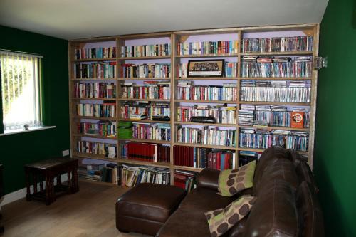 a living room with a large book shelf filled with dvds at B&B Dorwyn Manor in Avebury