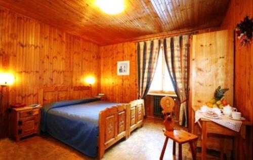 um quarto com uma cama, uma mesa e uma janela em Hotel Le Campagnol em Champoluc