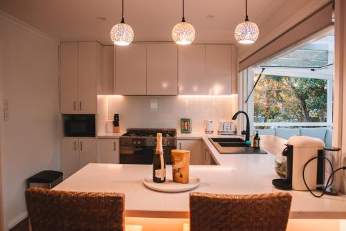 a kitchen with a table with bottles of wine on it at La Plage - A Cosy Cottage in Phillip Island in Cowes
