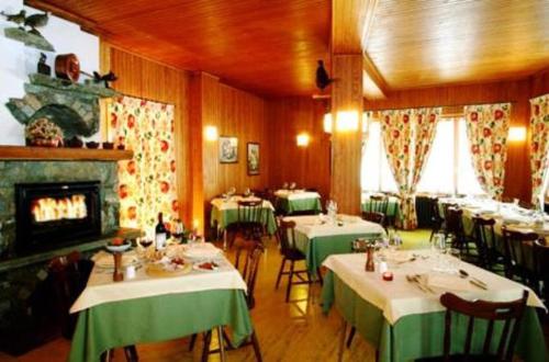 a restaurant with tables and chairs and a fireplace at Hotel Le Campagnol in Champoluc