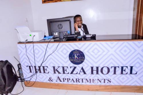 a man is sitting at a desk with a computer at The Keza Hotel and Apartments in Kigali