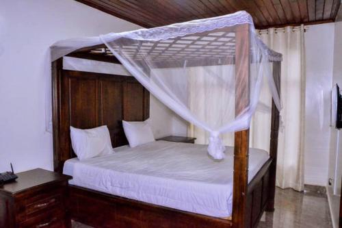 a bedroom with a wooden bed with a canopy at The Keza Hotel and Apartments in Kigali