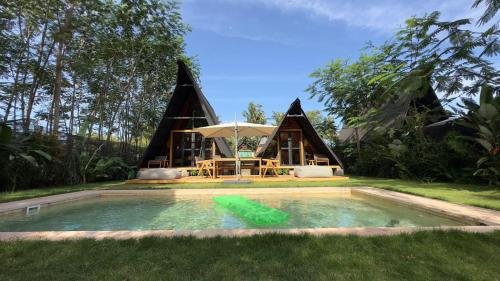a house with a pool and a table and an umbrella at Villa Verde the garden in Kejayan