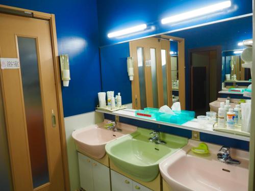 a blue bathroom with two sinks and two mirrors at Capsule Hotel Block Room in Tokyo