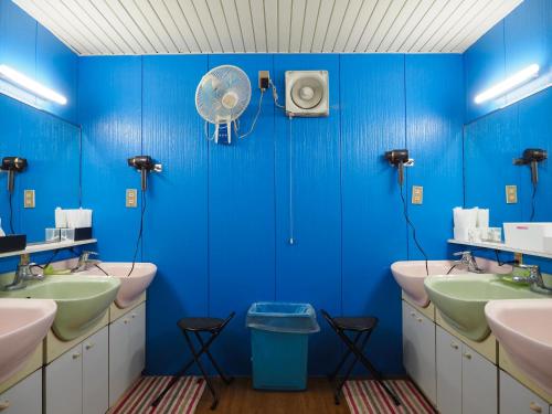 東京にあるカプセルホテルブロックルームの青いバスルーム(シンク4台、ファン付)