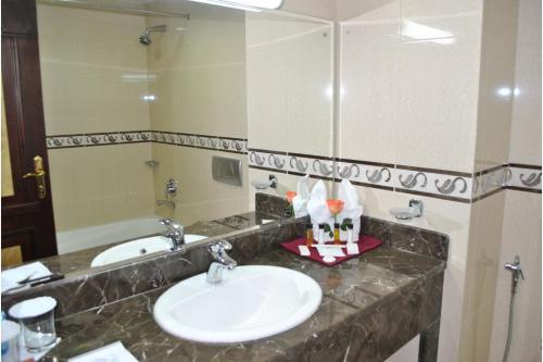 een badkamer met een wastafel en een grote spiegel bij Capital O 155 Dmas Hotel in Muscat