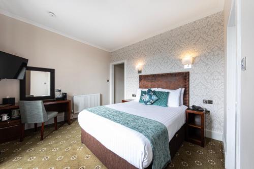 a hotel room with a bed and a desk and a television at Scotland's Spa Hotel in Pitlochry
