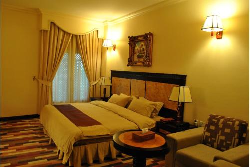 een slaapkamer met een bed, een bank en een stoel bij Capital O 155 Dmas Hotel in Muscat