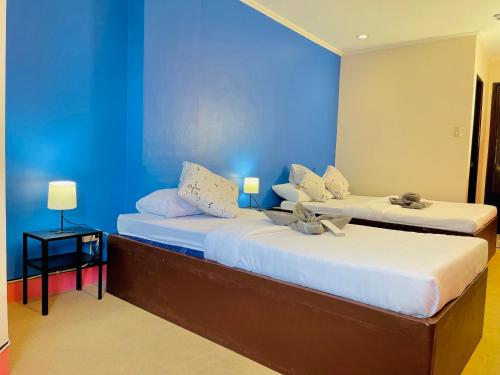 two beds in a room with a blue wall at RNJ Hotel in Baguio