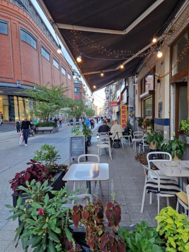 a patio with tables and chairs and plants on a street at C M Centrum II in Poznań