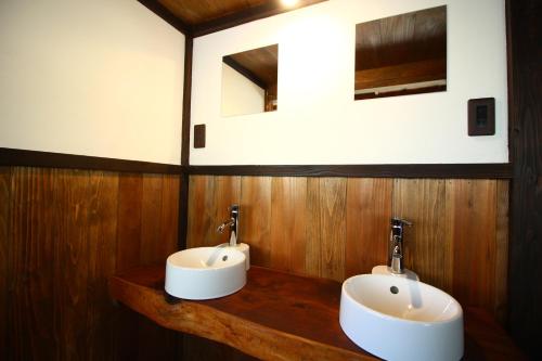 a bathroom with two sinks on a wooden wall at きよかわゲストハウス in Okutama