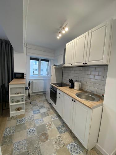 a kitchen with white cabinets and a sink at Central Studio Yoko in Craiova