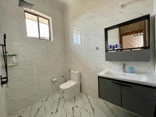 La salle de bains blanche est pourvue d'un lavabo et de toilettes. dans l'établissement Moderní Apartmány Raka, à Nungwi