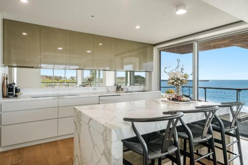 a kitchen with a table with chairs and a view of the ocean at ON THE Rocks - Yamba's Ultimate Absolute Beachdirft Residence - Holiday Yamba in Yamba