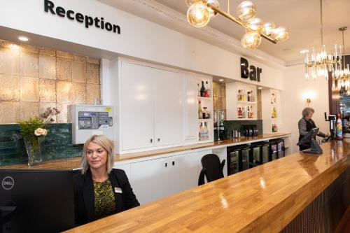 a woman sitting at a bar in a restaurant at Scotland's Spa Hotel in Pitlochry