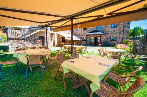 a group of tables and chairs under an umbrella at Hotel Rural La Bolera in Robles de Laciana