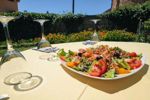 a plate of salad on a table with wine glasses at Hotel Rural La Bolera in Robles de Laciana