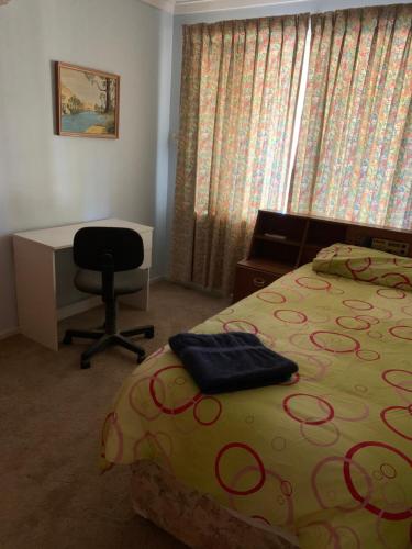 a bedroom with a bed and a desk and a chair at Hamersley Hacienda in Perth