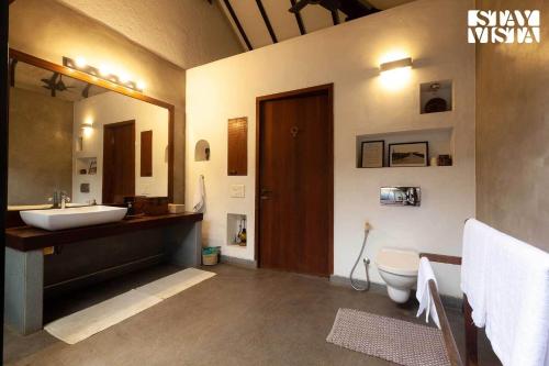 a bathroom with a sink and a toilet and a mirror at Wander Beyond by StayVista - Featuring a Bali-themed abode and a refreshing swimming pool in Alibaug