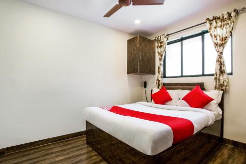 a bedroom with a large bed with red pillows at OYO Flagship Hotel Subodaya in Nerul