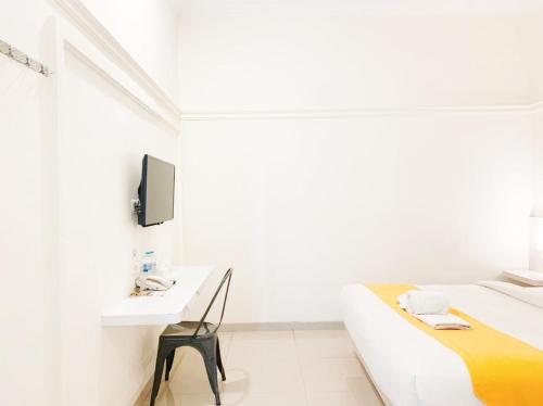 a white room with a bed and a desk at Victoria Bed & Breakfast in Malang