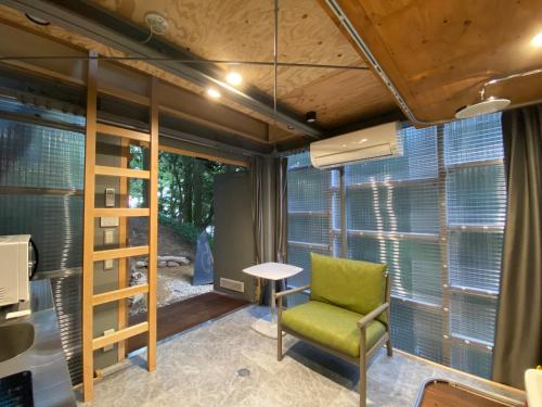 a room with a green chair and a table and windows at ThinkStay Mt.(シンクステイ・マウンテン) in Mikagechō