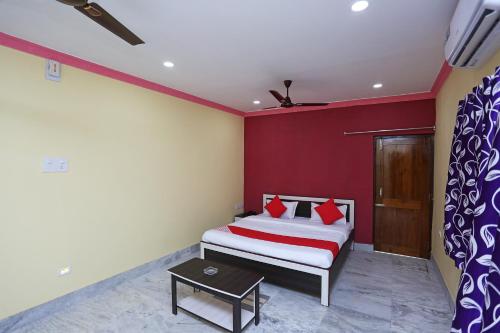 a bedroom with a bed and a red wall at OYO Flagship Moonlight Residency in Bhubaneshwar