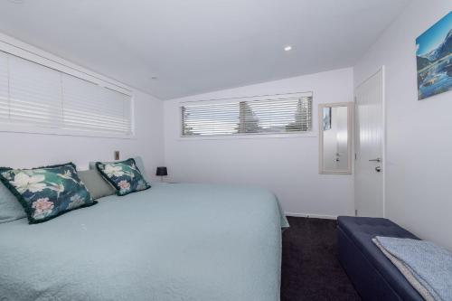 a white bedroom with a bed and a window at Mountain View Apartment in Wanaka