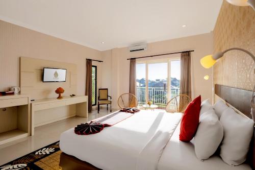 1 dormitorio con 1 cama blanca grande con almohadas rojas en The Kanjeng Hotel Kuta, en Kuta