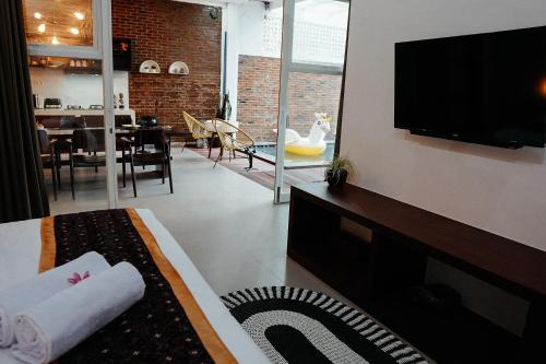 a living room with a bed and a tv and a dining room at Emka Villa Traditional Minimalist in Malang