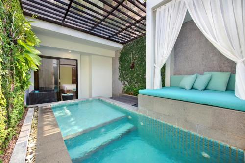 a pool in a backyard with a bed next to it at Mercure Bali Legian in Legian