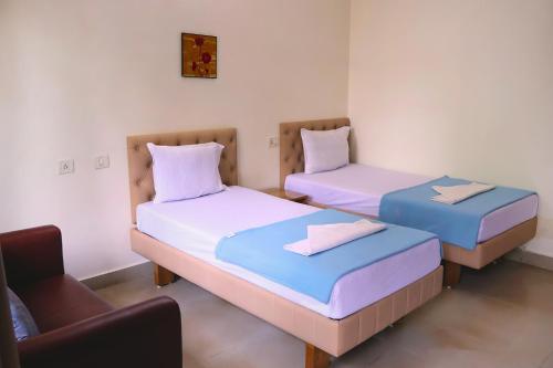 two beds in a room with a chair at FabEscape Orient Royal in Calangute