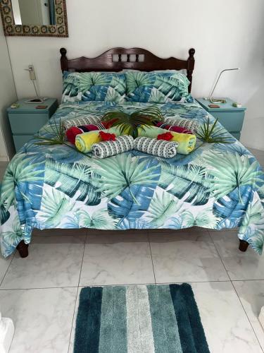 a bedroom with a bed with a blue and green comforter at Royal Bay Apartment in Anse Royale