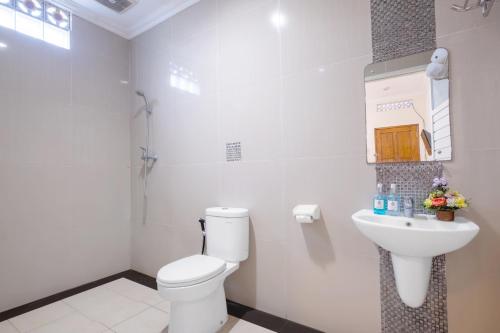bagno bianco con servizi igienici e lavandino di The Kanjeng Hotel Kuta a Kuta