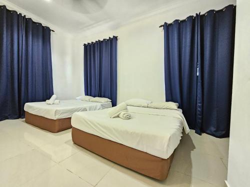 two beds in a room with blue curtains at RVH Kuala Terengganu in Kuala Terengganu