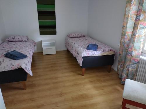 two twin beds in a room with a wooden floor at Saarnimaja in Hämeenlinna