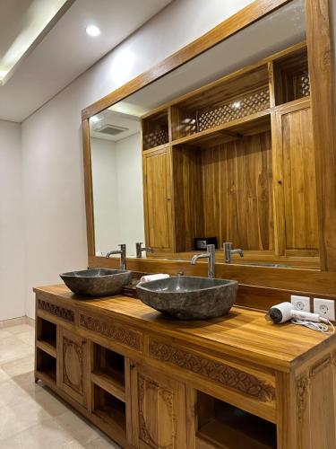 two sinks on a wooden counter with a mirror at Gyanesh Villa in Ubud