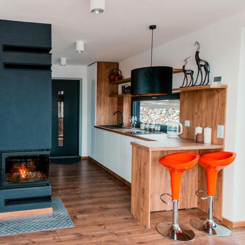 a kitchen with orange bar stools and a fireplace at Domek PodMaglem 